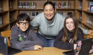 Una mujer y dos niños en una biblioteca escolar