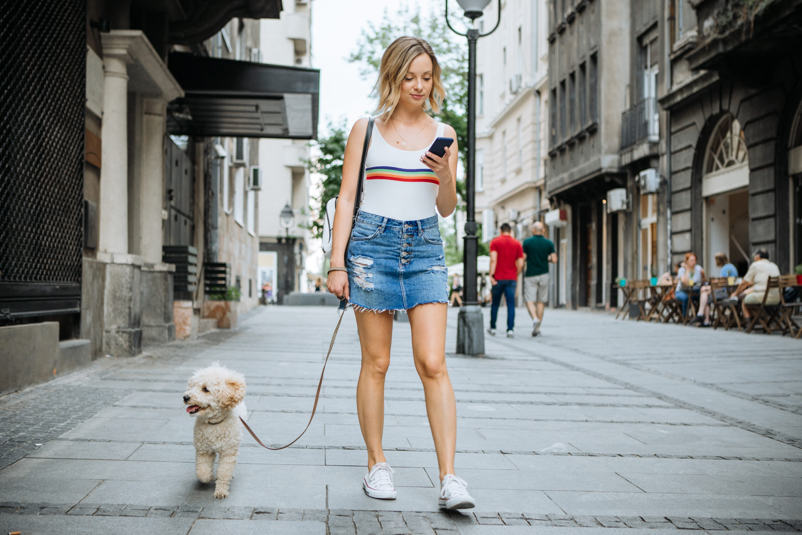 Mujer mira el teléfono mientras pasea al perro