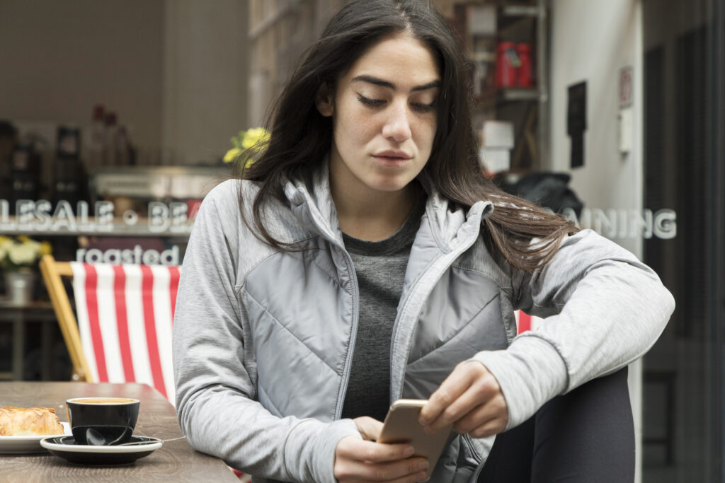 Una mujer se sienta y mira su teléfono