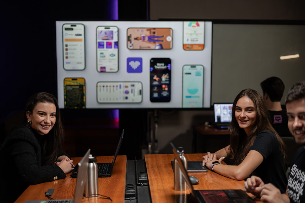 Várias pessoas sentadas em uma mesa com uma tela de projetor ao fundo