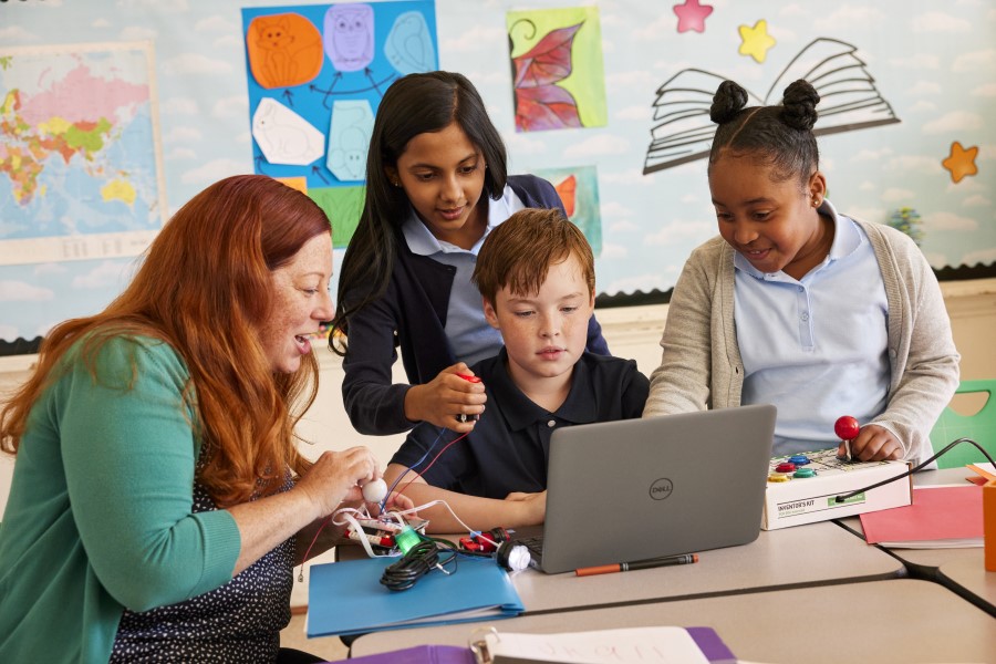 Educadora y sus alumnos frente a una laptop