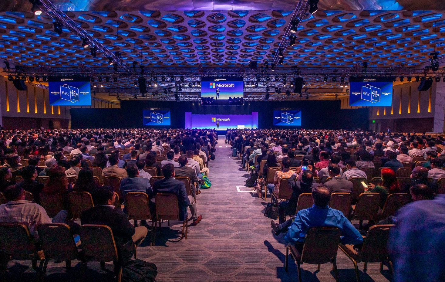 Imagen de una salón de conferencias lleno, con el escenario al fondo