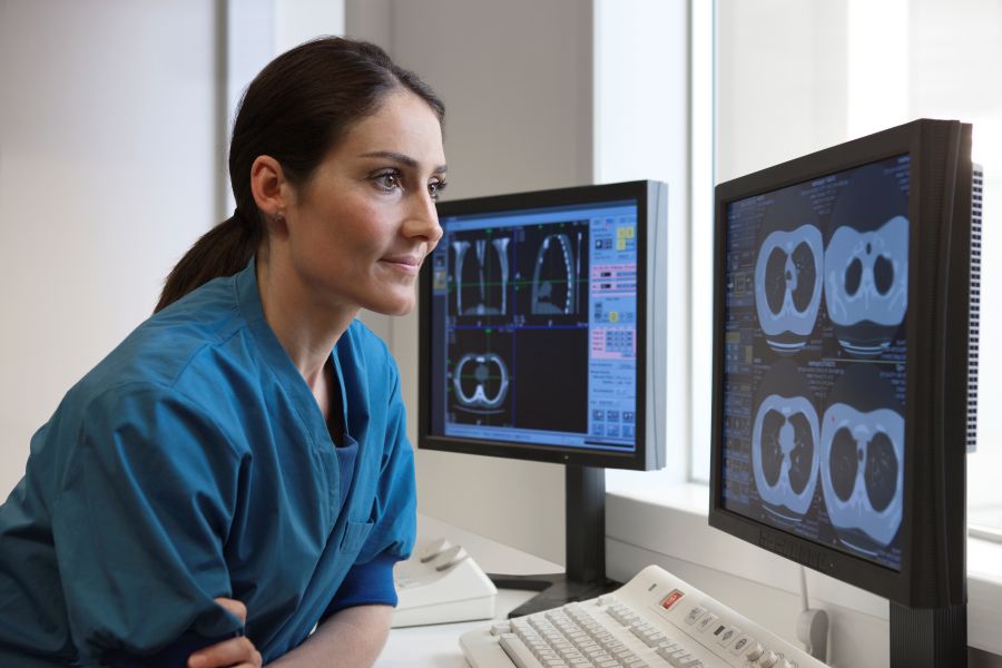Una mujer con uniforme azul mirando pantallas de computadora
